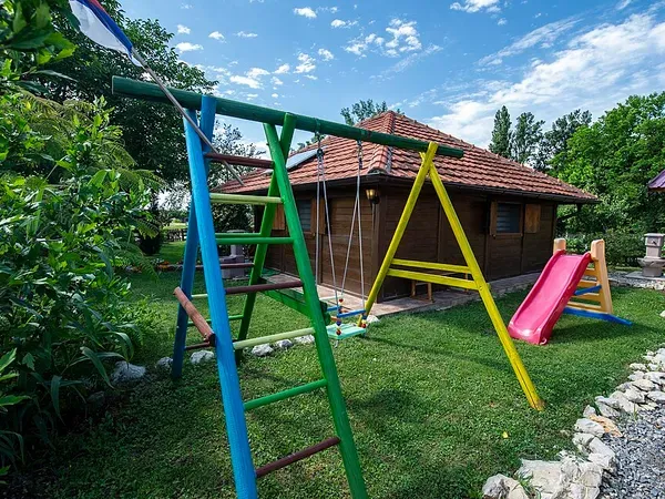 Дитячий ігровий майданчик біля дерев'яного будинку