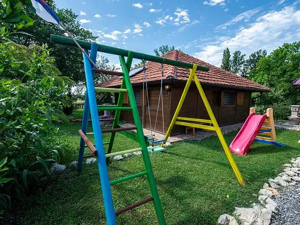 Дитячий ігровий майданчик біля дерев'яного будинку
